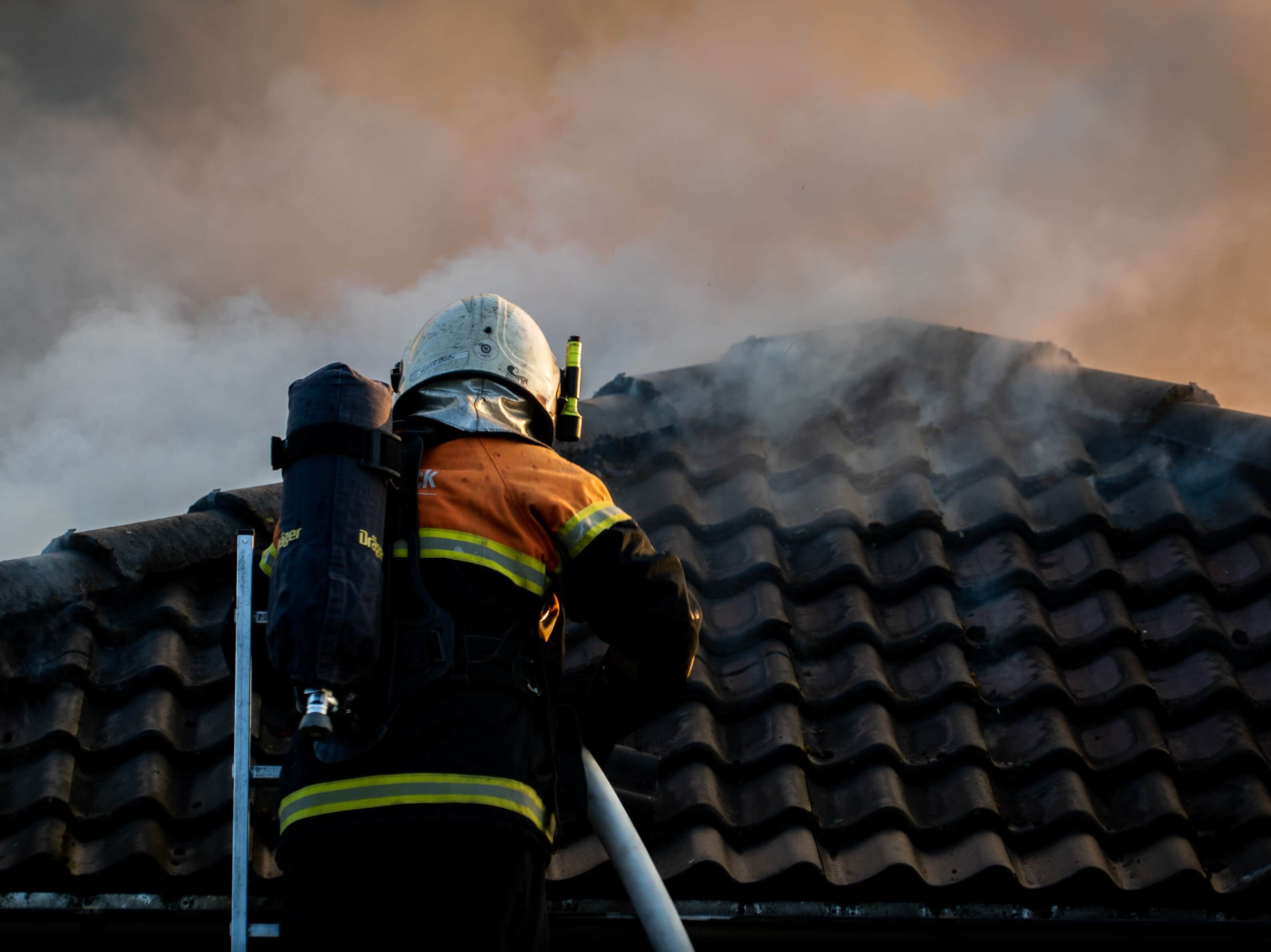 Brandmand slukker ild i tag på hus